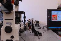 A set of photographs of an unknown experiment involving a microscope, an unknown circuit board and some sensor which is connected to a computer.