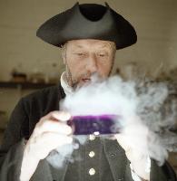A man dressed in 16th century dress holding a substance releasing what is likely carbon dioxide, possibly as an alchemy related demonstration.  2 images.